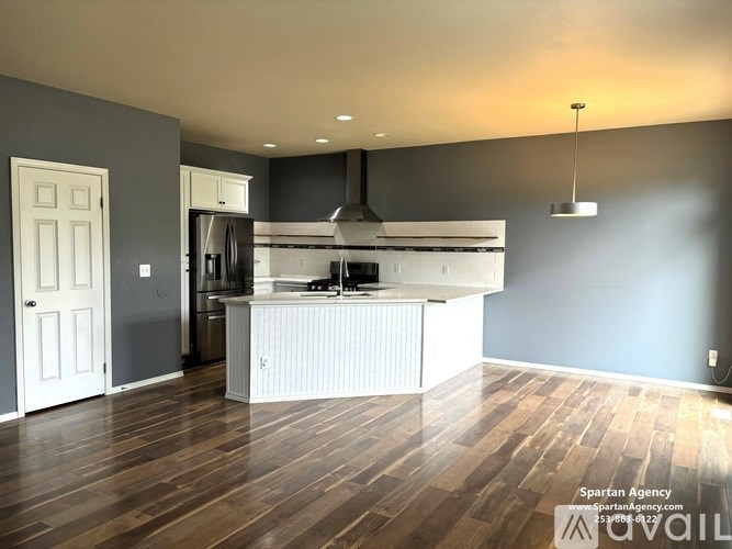 A kitchen with a white island and wooden floors.