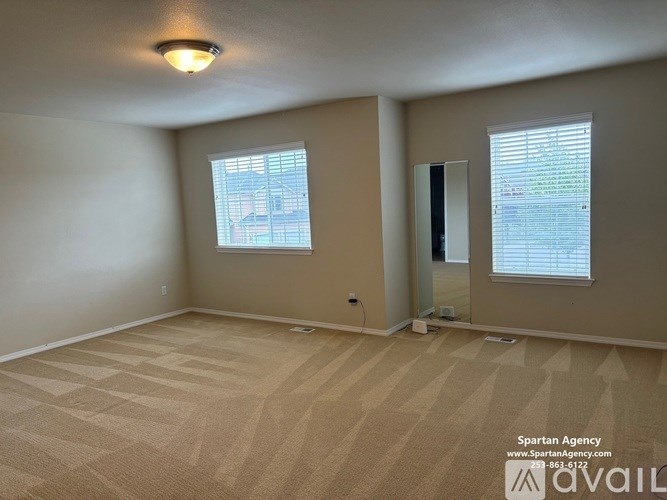 A room with beige carpeting and a door leading to a balcony.