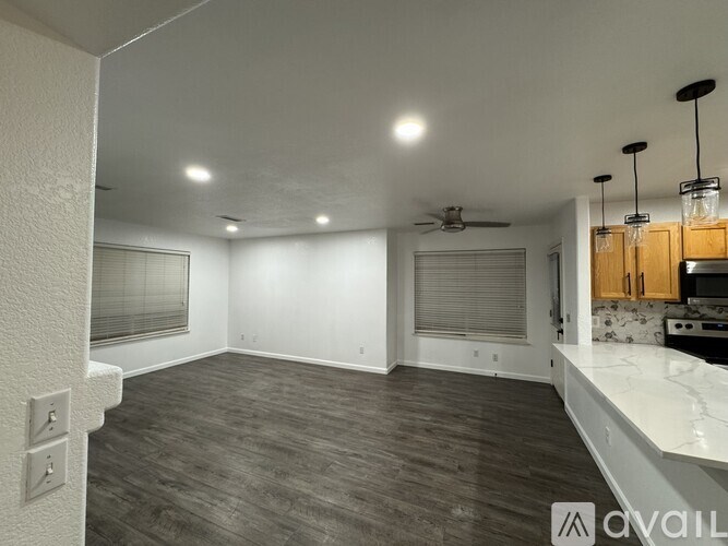 A spacious room with a ceiling fan and a kitchen area with wooden cabinets.