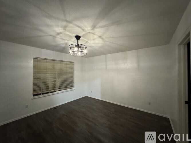 A room with a wooden floor and a window with blinds.