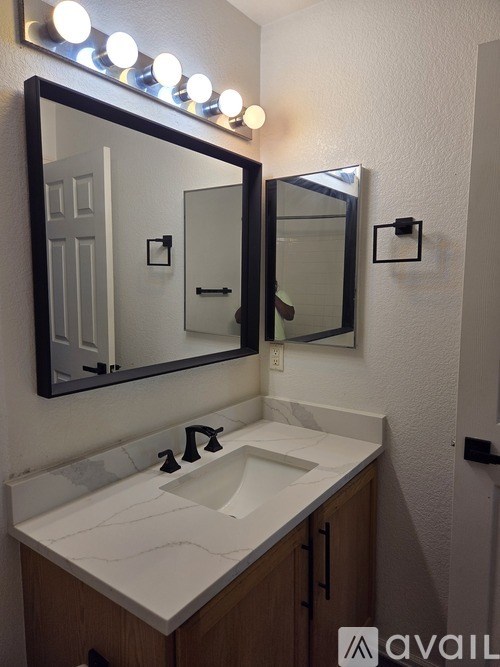 A bathroom with a sink, mirror and lights.