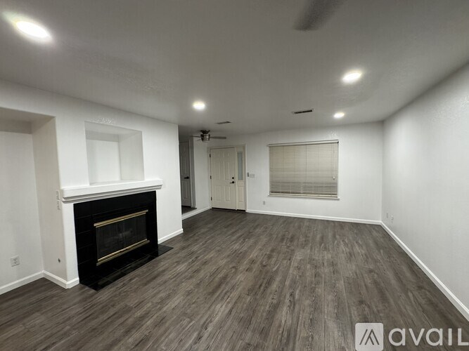 A spacious room with a fireplace and wood flooring.