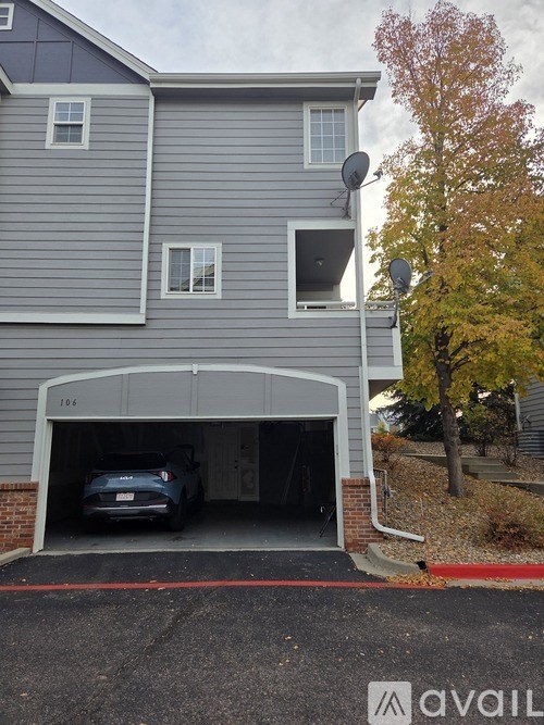 A car is parked in a garage attached to a grey house.
