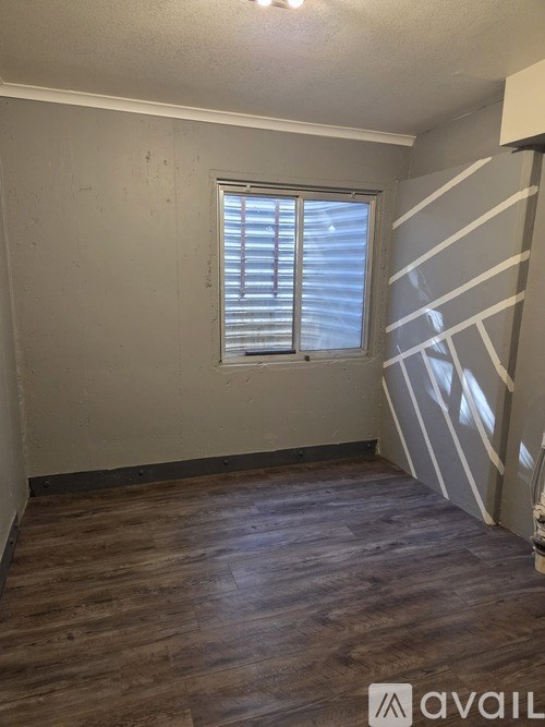A room with wooden flooring and a window with blinds.