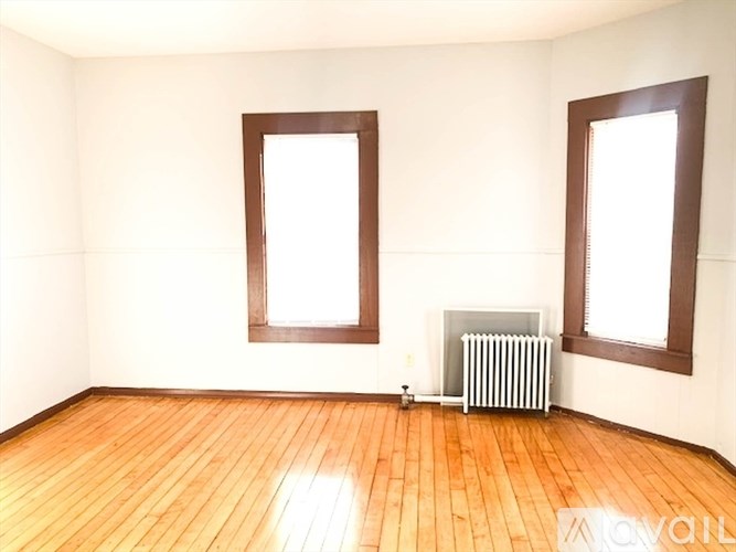 A room with wooden floors and two windows.