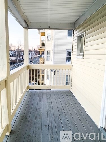 A balcony with a wooden floor and white railings.