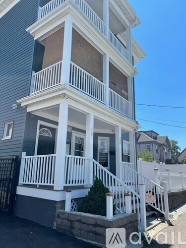 A two-story house with a white balcony and a black gate.