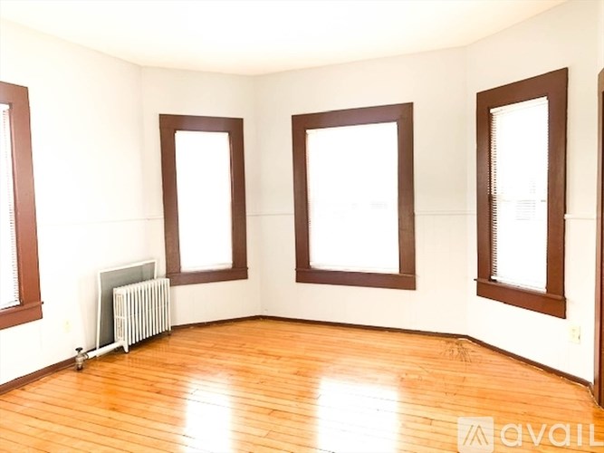 A room with wooden floors and three windows.