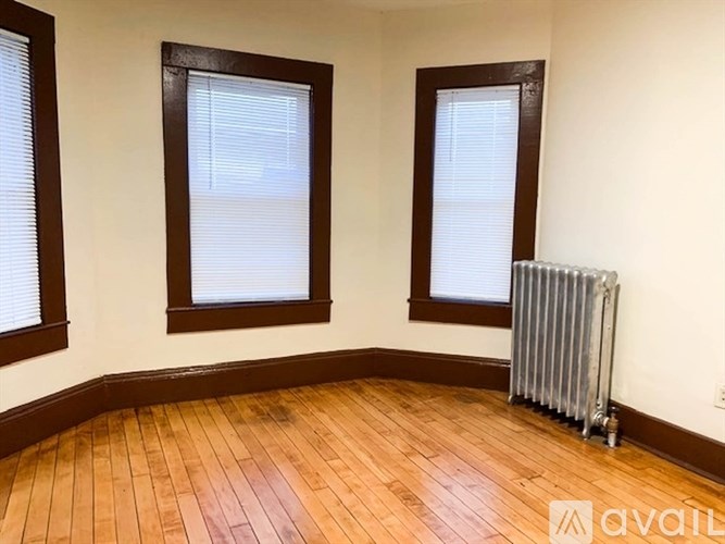 A room with wooden floors and two windows with blinds.