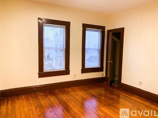 A room with wooden floors and two windows.