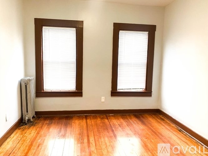 A room with wooden floors and two windows.