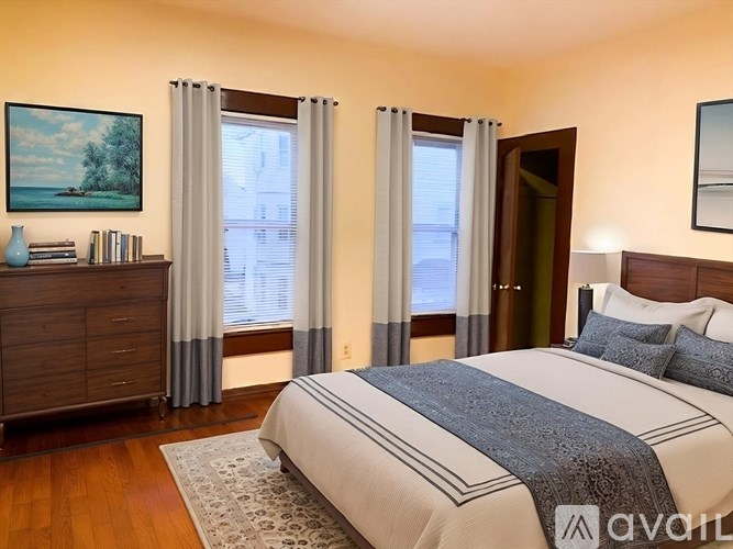 A bedroom with a large bed and a painting on the wall.