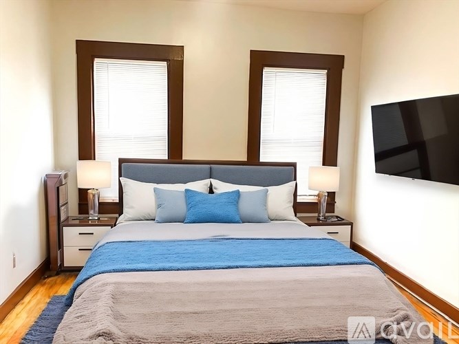 A bedroom with a large bed and a flat screen TV mounted on the wall.