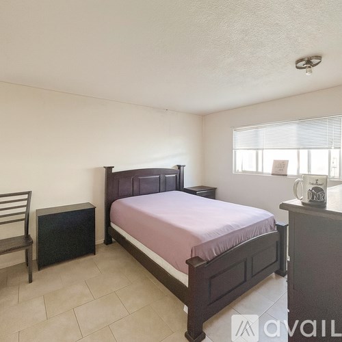 A bedroom with a bed, nightstand, and chair.