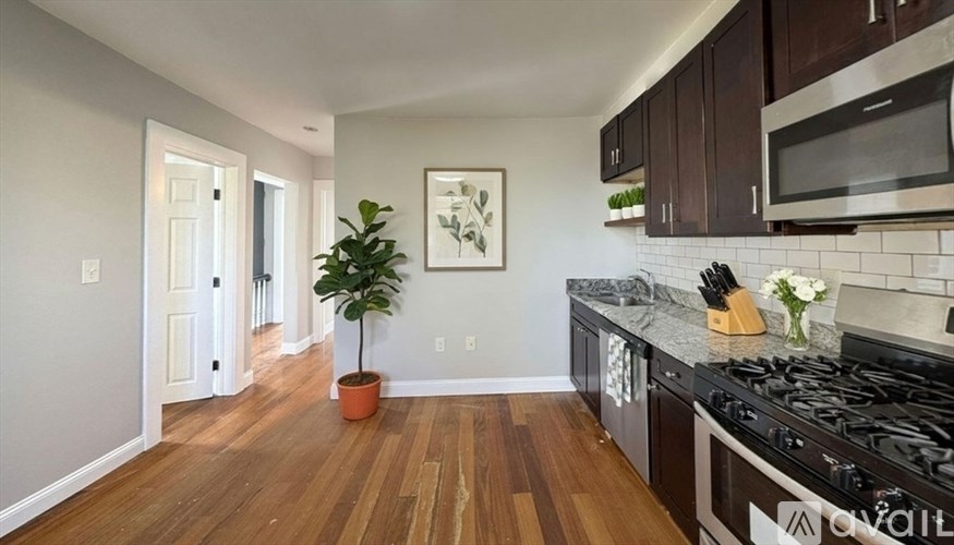 A kitchen with a black stove top oven and wooden floors.