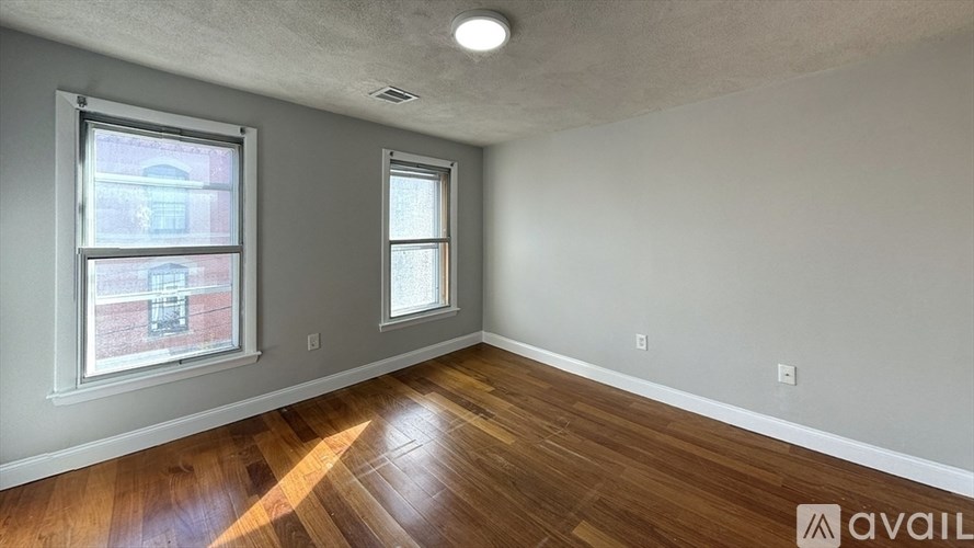 A room with wooden floors and two windows.