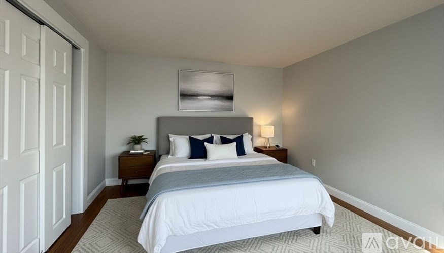 A bedroom with a bed, nightstand, and lamp.