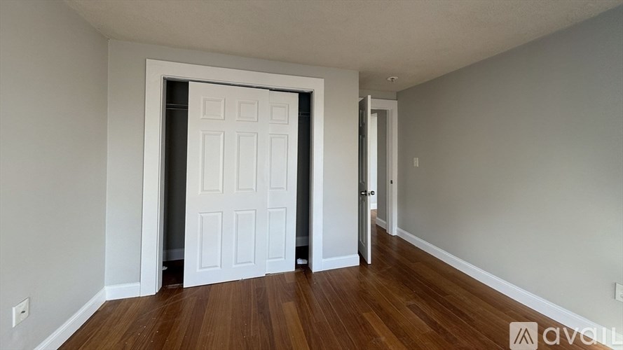 A room with a white door and wooden floors.