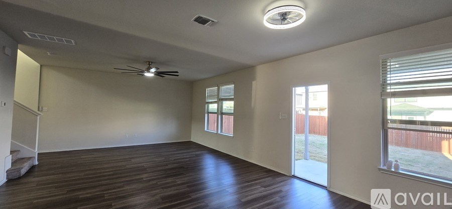 A spacious room with wooden floors and a ceiling fan.