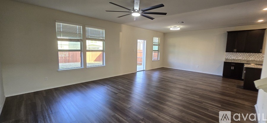 A spacious room with wooden floors and a ceiling fan.