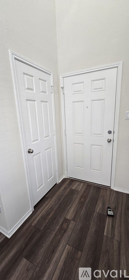 Two white doors in a room with wooden flooring.