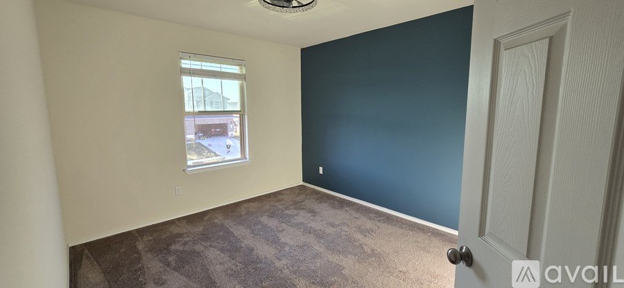 A room with a carpeted floor, a window, and a door.