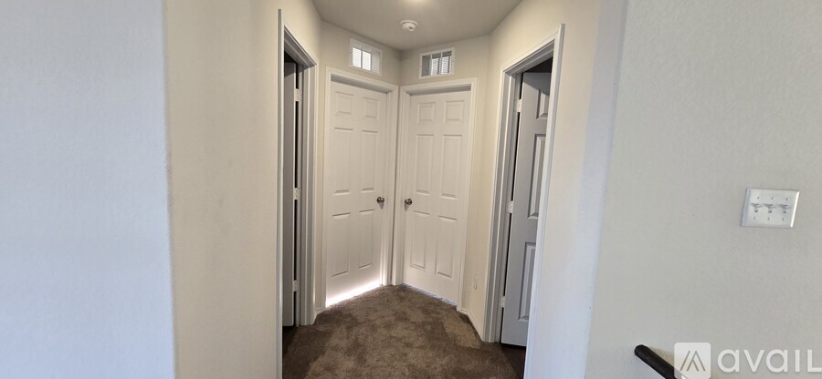 A hallway with white doors and a carpeted floor.