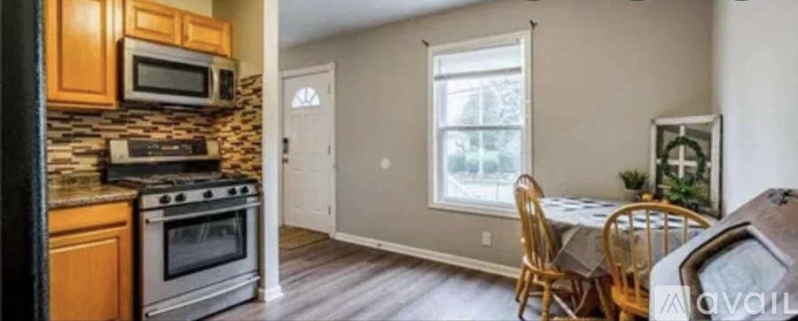 A kitchen with a stone backsplash and wooden cabinets.