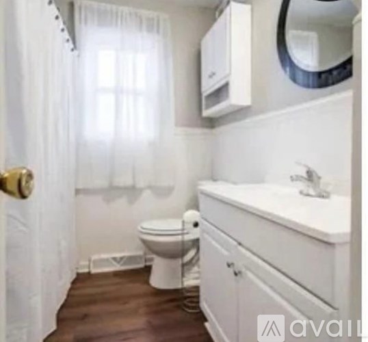 A white bathroom with a toilet, sink, and mirror.