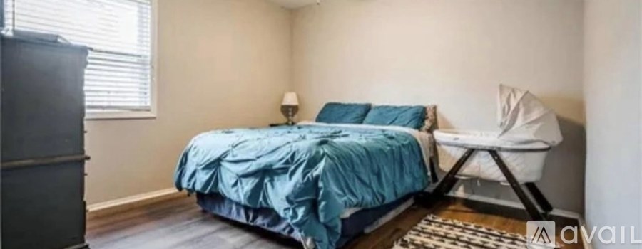 A bedroom with a bed, a chair, and a crib.