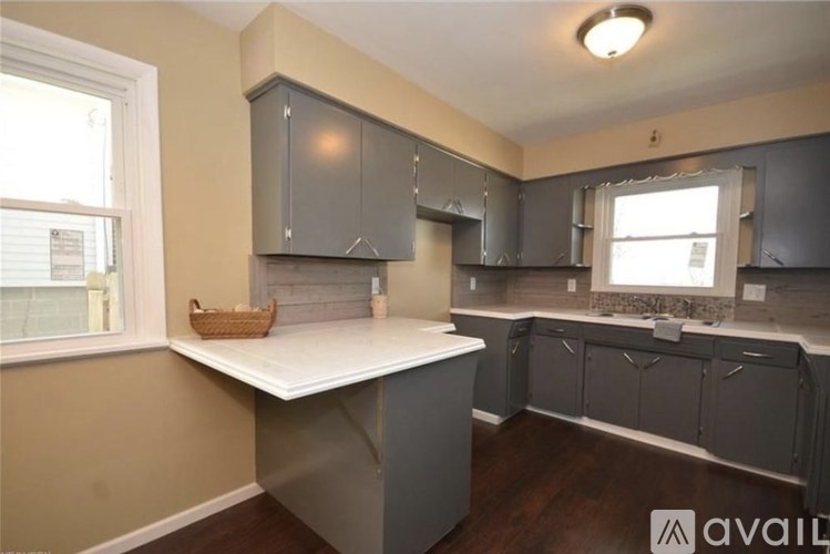 A kitchen with a white countertop and grey cabinets.