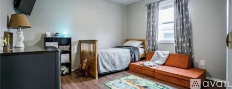 A bedroom with a bed, a nightstand, a dresser, and a window with curtains.