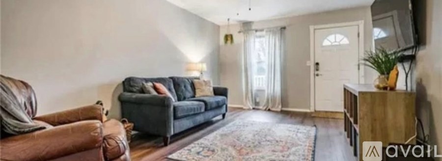 A living room with a grey couch, a brown leather chair, a wooden cabinet, and a rug.