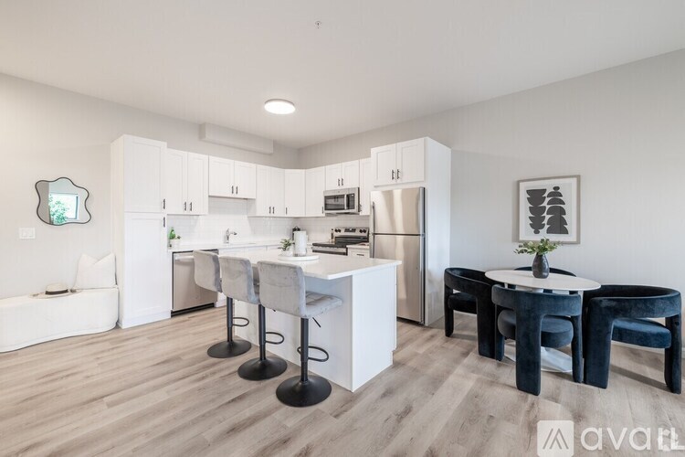 A kitchen with white cabinets and a white island with a table and chairs.