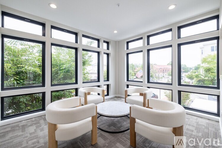 A room with a table and chairs in front of large windows.