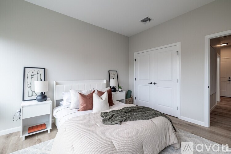 A bedroom with a large bed and a white nightstand with a lamp.