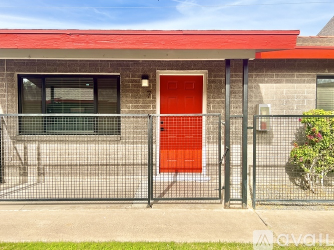 A red door is on the right side of a grey building.