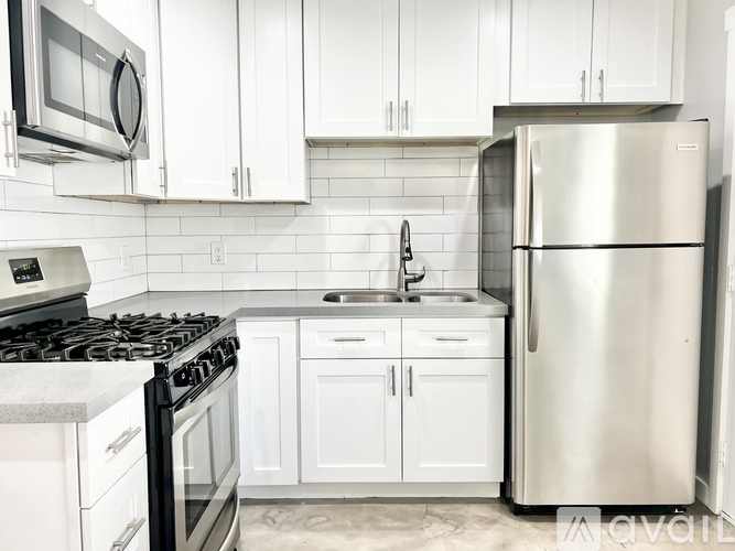 A kitchen with white cabinets and a stainless steel refrigerator.