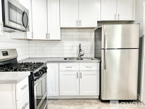 A kitchen with white cabinets and a stainless steel refrigerator.
