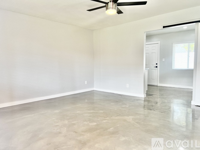 A spacious room with a ceiling fan and a door leading to another room.
