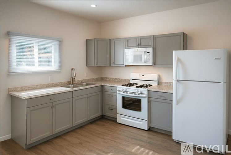 A kitchen with a white refrigerator, sink, and cabinets.