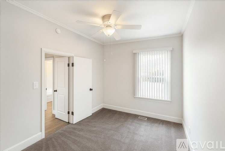 A room with a ceiling fan and a window with blinds.