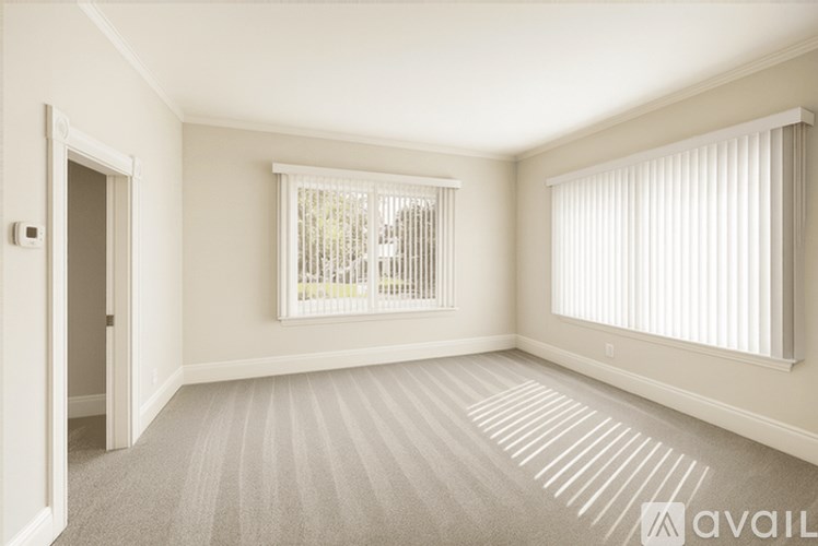 A room with a carpeted floor and a window with blinds.