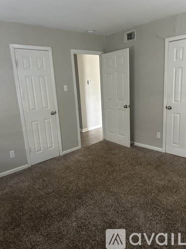 A room with three doors and a carpeted floor.