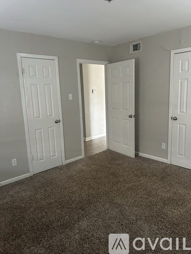 A carpeted room with three doors and a logo that says "avaiL".