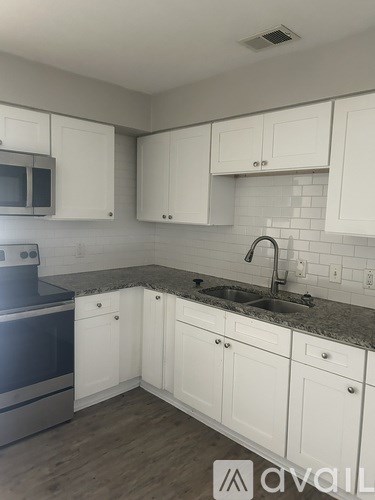 A kitchen with white cabinets and a granite countertop.