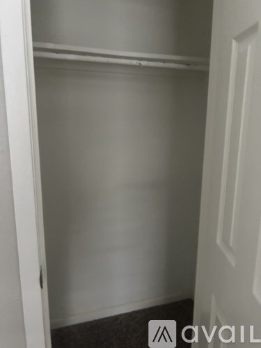 A white closet with a shelf and a door.