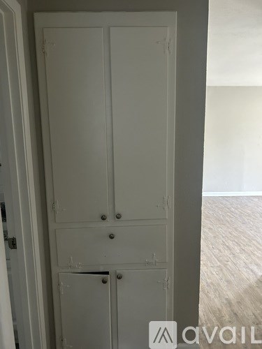 A tall white wardrobe with two doors and two drawers is in a room.