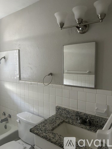 A bathroom with a granite counter top and white tiles.