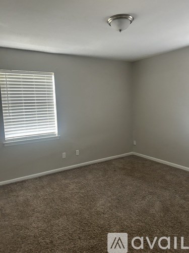 A room with a carpeted floor and a window with blinds.